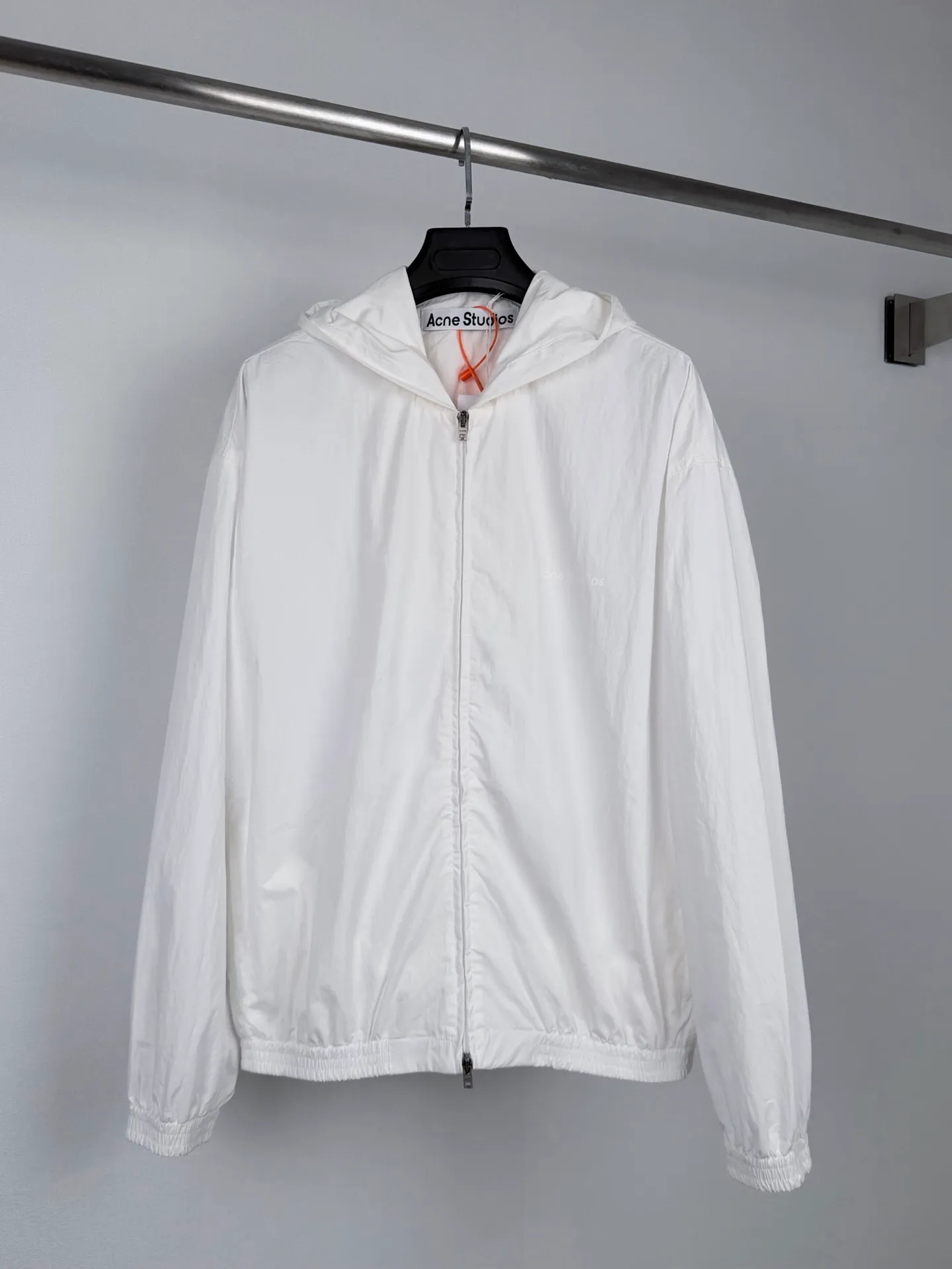 Acne Studios logo-printed hooded jacket. Custom-made Lanxu poplin. Breathable. Comfortable and skin-friendly. Obsidian black dip-dyed body. Native matte texture, calm and restrained. Contrast topstitching is extended along the seams. Architectural lines are used to outline the three-dimensional silhouette of the body. Layers of tension are spread on a dark black background. The hooded silhouette is relaxed and stretched. ACNE STUDIOS STOCKHOLM hot stamping printed static fabric on the back. The light and shadow are looming, restrained and engraved with the Stockholm brand narrative. The full zipper opening and closing is neat and easy. The elasticated hem and cuffs create a relaxed and short silhouette. Integrate Stockholm's minimalist pioneer genes into the functional jacket to interpret the cool and restrained high-end elegance of Northern Europe. Process 1: Using hot stamping printing process. The printing is calibrated through multiple layers. The heat transfer film and high-temperature fusion pigments are used to transfer the pattern on the fabric. High-temperature pressing of the fabric to fix the transfer pattern. Process 2: Template machine bag opening. The preset template guides the position, shape and size of the bag opening. The accuracy ensures the quality of the bag opening effect. Accessories: Customized 1:1 Acne placket zipper. Customized 1:1 Acne pocket zipper. Customized 1:1 Acne snap button. Customized 1:1 Acne trademark. Version: Loose version. Size: 44 46 48 50